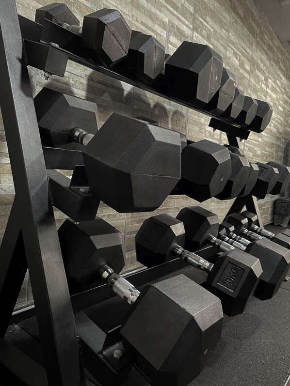 A rack of black dumbbells with weight markings, set against a tiled wall. - Ker Recoleta Hotel (Buenos Aires)