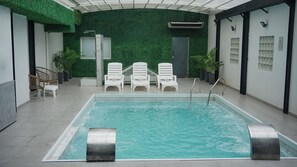A swimming pool with a few lounge chairs and a wall with a green textured design. - Ker Recoleta Hotel (Buenos Aires)