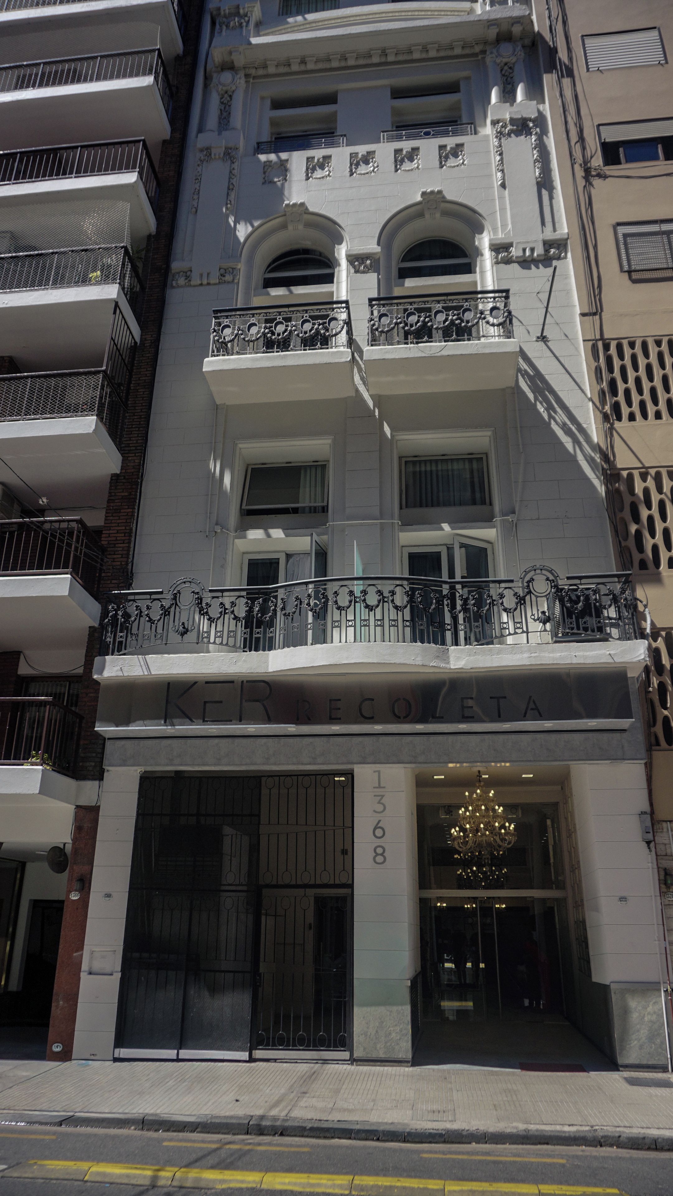 Um edifício de vários andares com entrada imponente, grandes janelas e uma varanda decorativa.