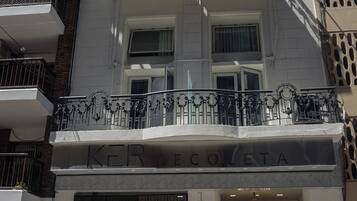Um edifício de vários andares com entrada imponente, grandes janelas e uma varanda decorativa.