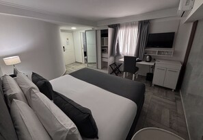 A hotel room with a bed, a desk, a chair, a television, and a kitchenette. - Ker Recoleta Hotel (Buenos Aires)