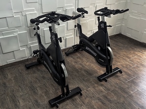 Two stationary bikes in a room with a patterned wall and wooden flooring. - Ker Recoleta Hotel (Buenos Aires)