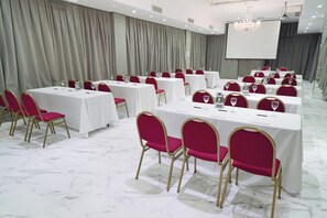 A conference room with rows of tables and chairs, a projector screen, and a chandelier. - Ker Recoleta Hotel (Buenos Aires)