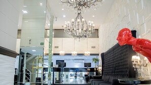 A lobby with a chandelier, a reception desk, a sofa, and a large red sculpture. - Ker Recoleta Hotel (Buenos Aires)