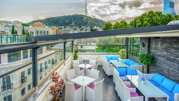Une terrasse sur le toit avec des sièges extérieurs, une vue sur le paysage urbain et une montagne en arrière-plan.