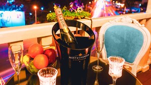 Une table avec une bouteille de champagne, des verres et un panier de fruits.