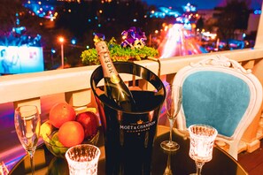 A table with a champagne bottle, glasses, and a fruit bowl. - River Side Hotel (Tbilisi)