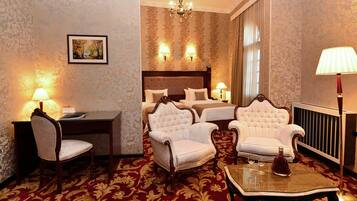 A hotel room with a large bed, two armchairs, a desk, and a table with glasses.