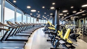 A gym with treadmills and weight machines, large windows, and a city view. - River Side Hotel (Tbilisi)