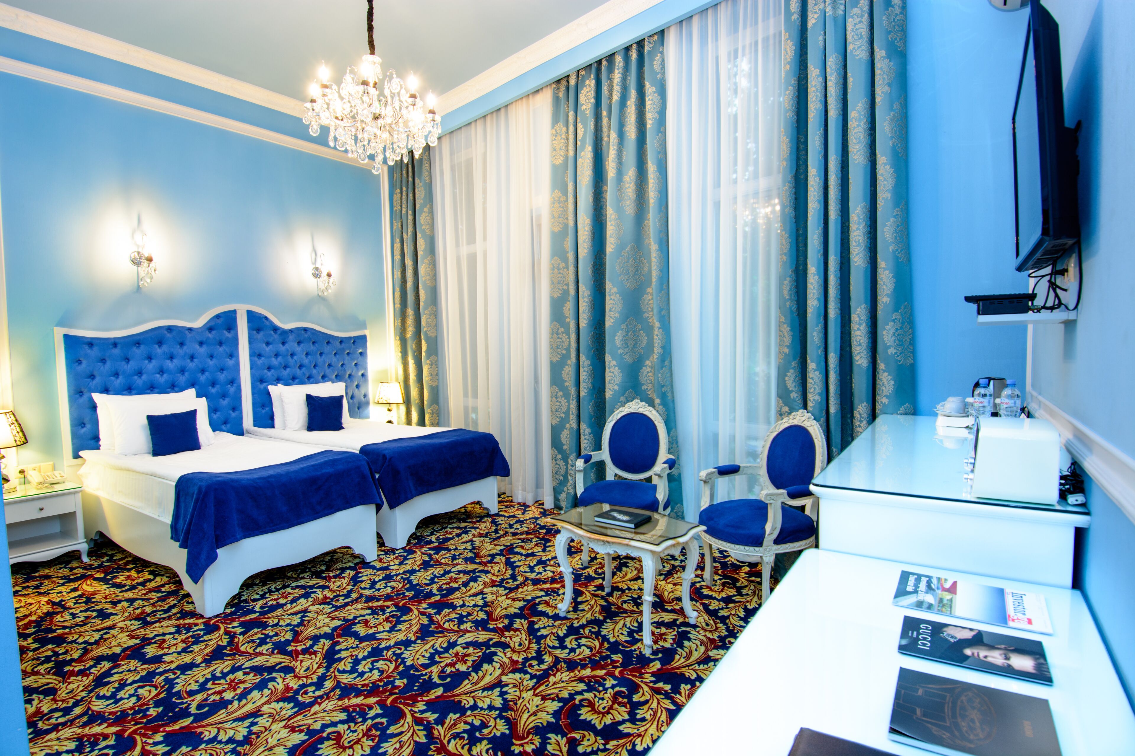 Una habitación de hotel con una cama grande, dos sillas, una mesita y un televisor.