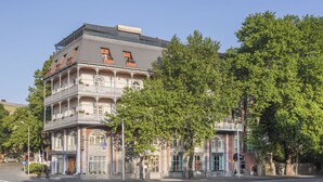 A multi-story building with a balcony on the second floor, a storefront on the ground floor, and trees in front. - River Side Hotel (Tbilisi)