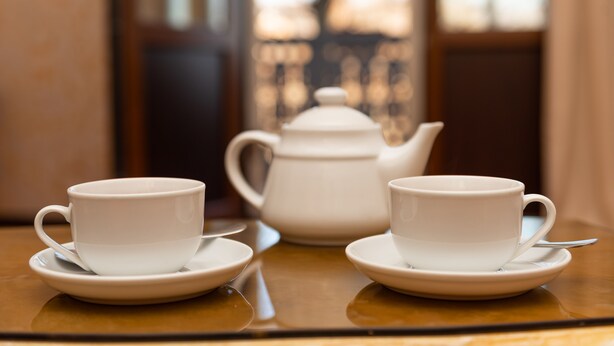 Two white cups and a teapot on a reflective table. - River Side Hotel (Tbilisi)