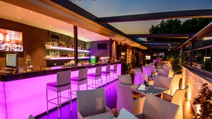 A bar area with a counter, seating, and a view of the outdoors. - River Side Hotel (Tbilisi)