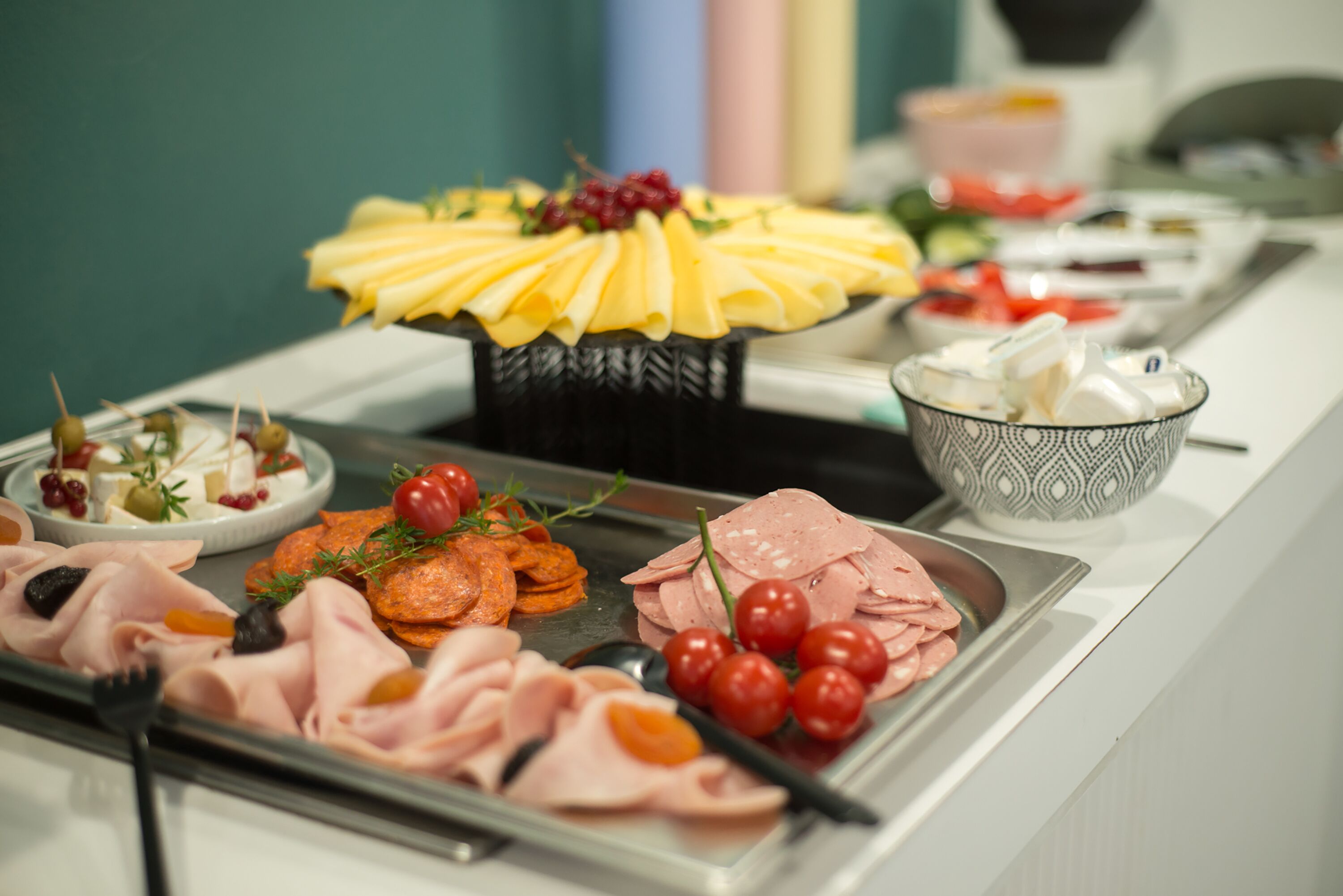 A buffet with various food items including cheese, meats, and vegetables.