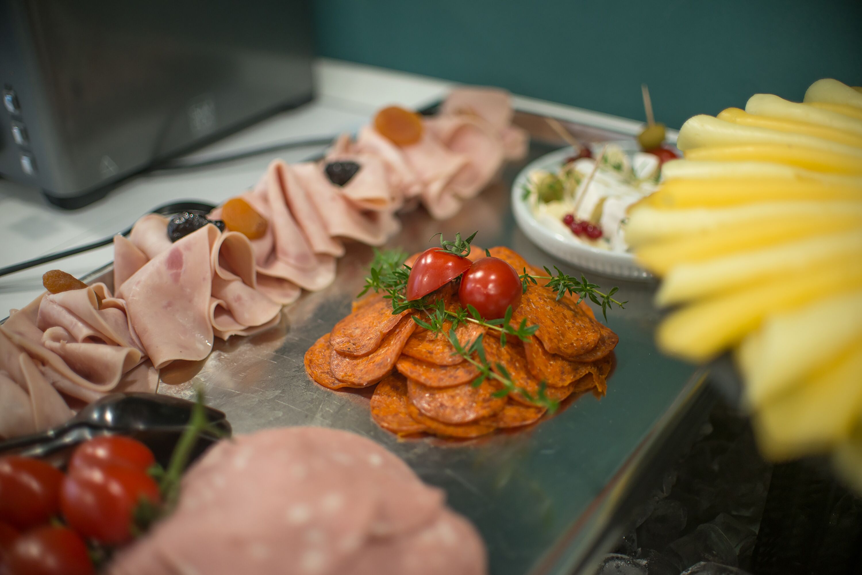 Una variedad de alimentos, como embutidos, tomates y queso, dispuestos en una bandeja.