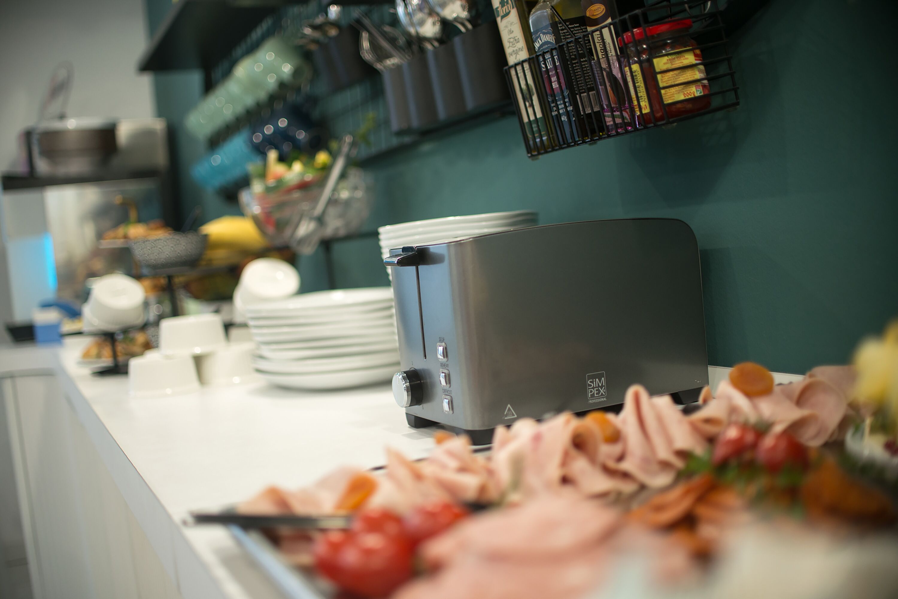 A kitchen counter with a toaster, plates, and a variety of food items.