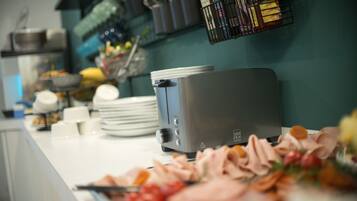 A kitchen counter with a toaster, plates, and a variety of food items.