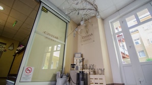 L’entrée d’un hôtel, avec une porte en verre, une enseigne indiquant « HÔTEL CIVITAS » et une branche décorative suspendue au plafond.