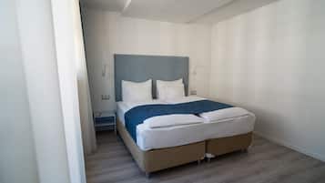 A modern bedroom with a bed, a nightstand, and a wall-mounted lamp.