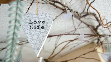 Ein dekoratives, herzförmiges Ornament mit der Aufschrift 'Love Life', das an einem Zweig hängt.