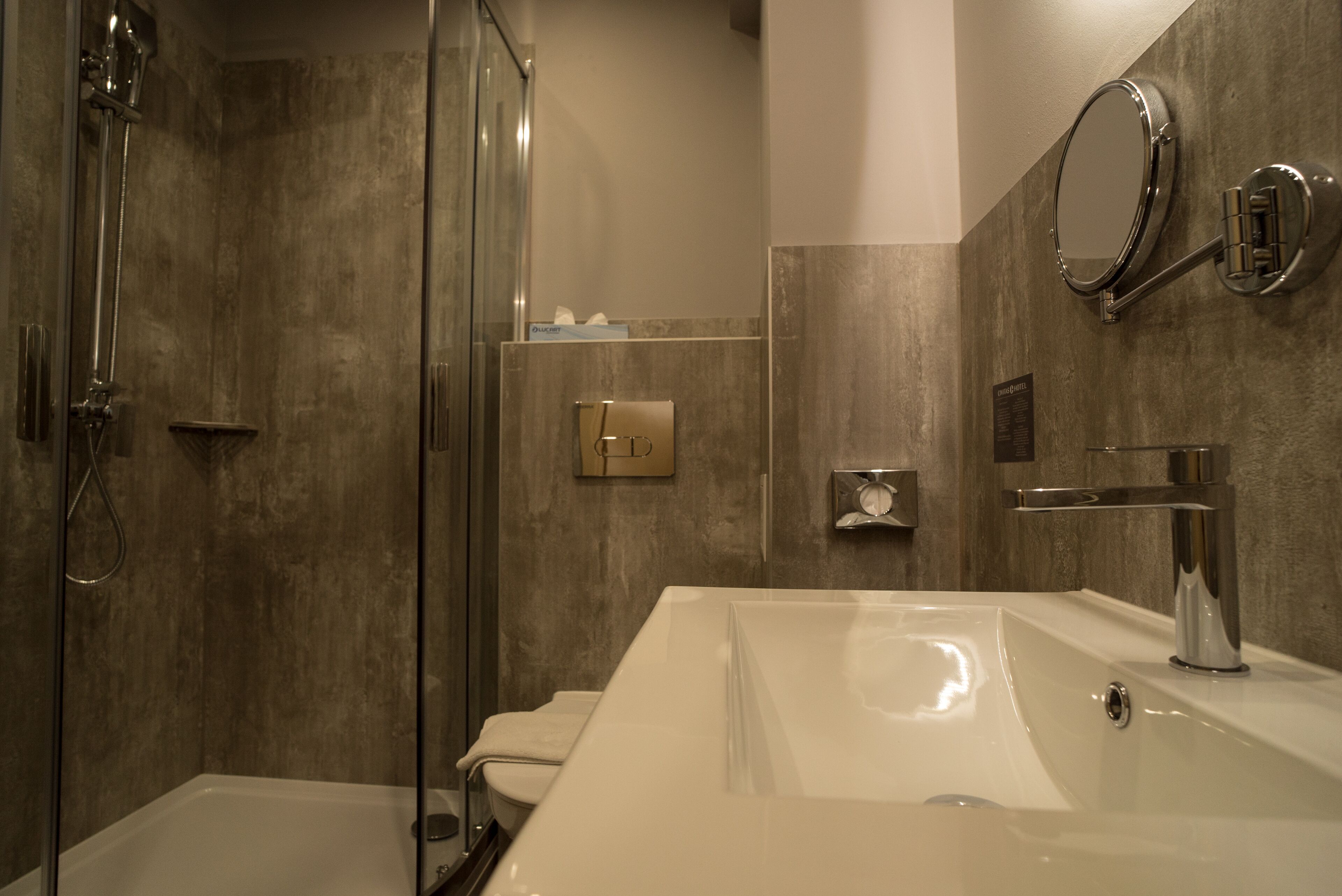 A modern bathroom with a glass-enclosed shower, a large white sink, and a mirror.