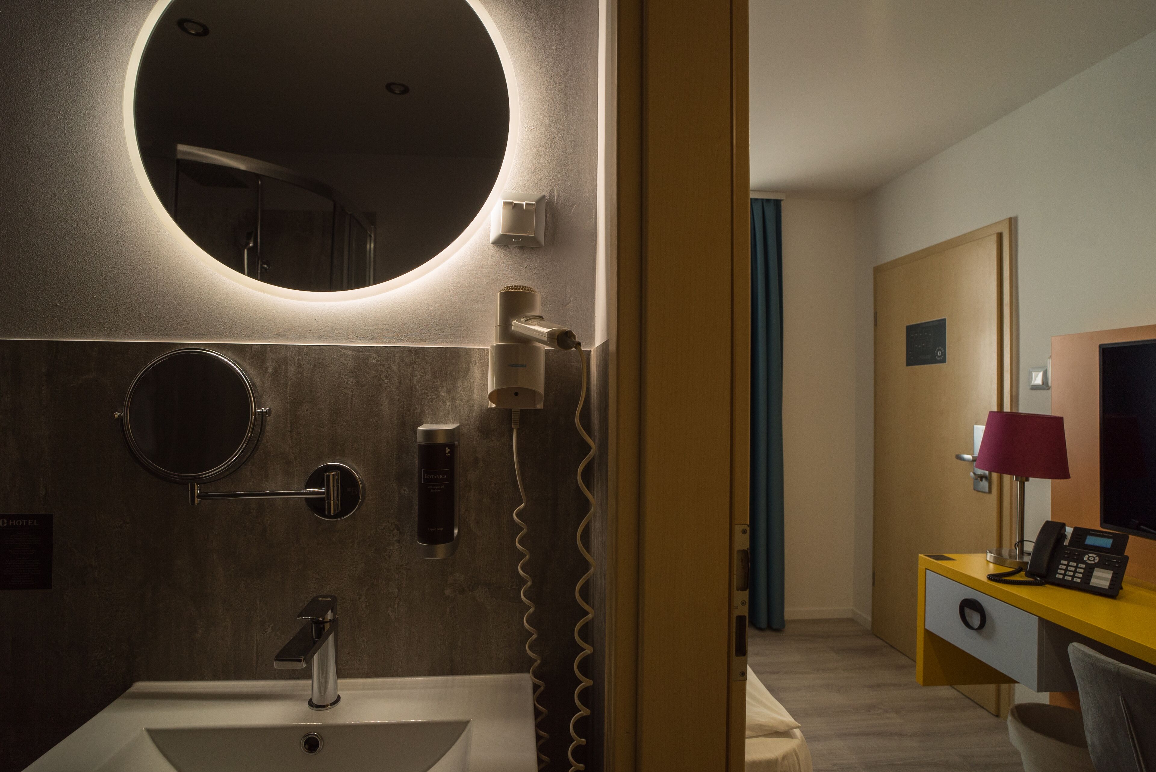 A modern bathroom with a round mirror, a sink, and a hairdryer.