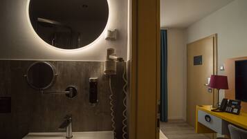 A modern bathroom with a round mirror, a sink, and a hairdryer.