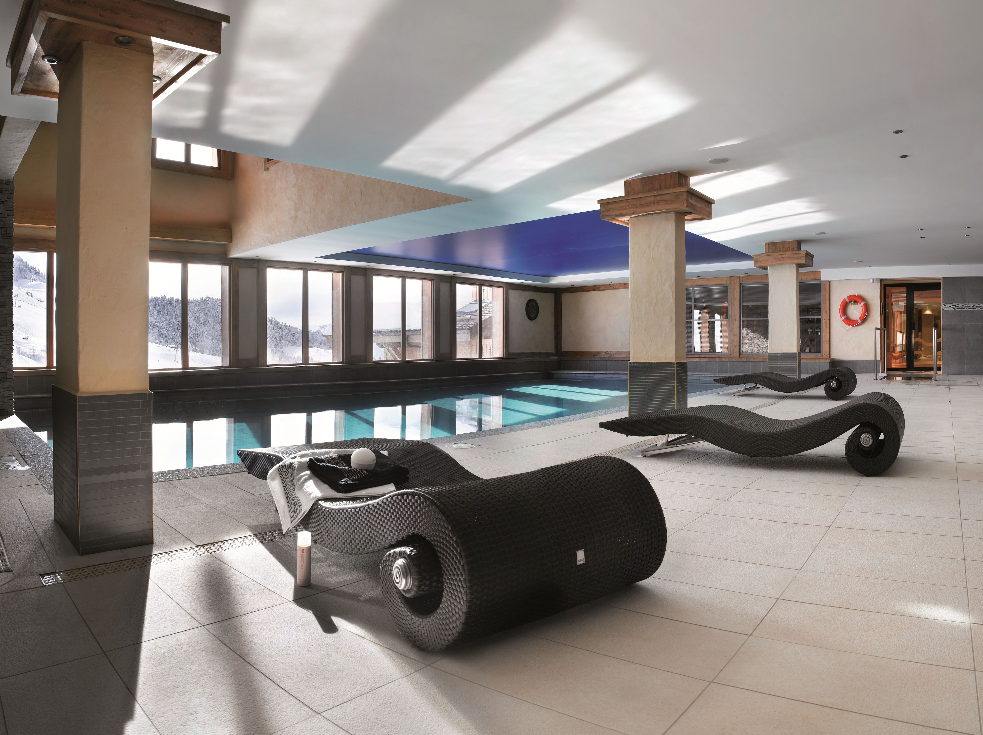 A modern indoor swimming pool with clear views of a snowy landscape through large windows.