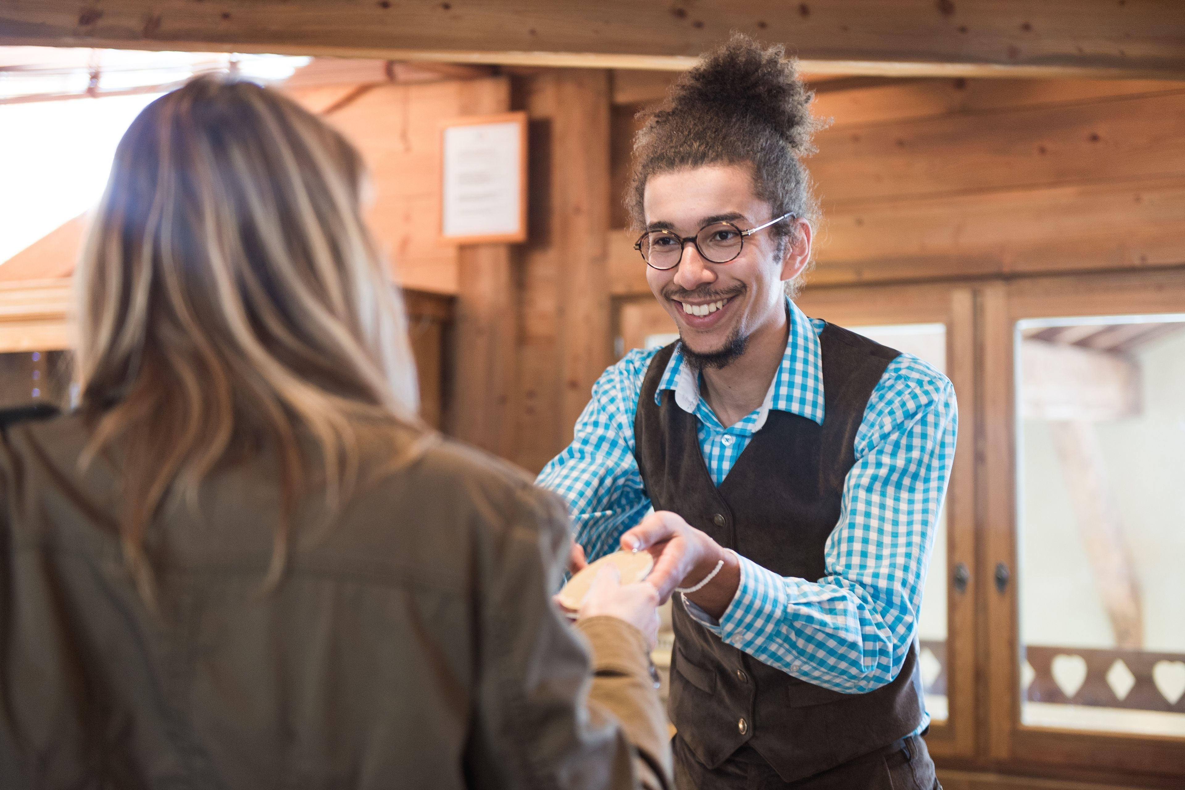 A wooden interior with a person handing over a card to another person.