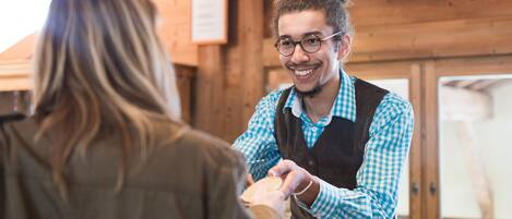 A wooden interior with a person handing over a card to another person.