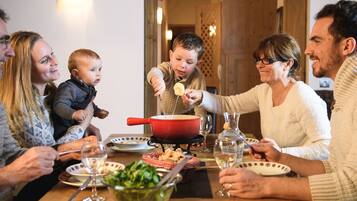 Family gathers around the table for a meal, surrounded by plates, cutlery, and a variety of dishes.