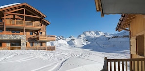Eine Holzhütte mit Balkon und Blick auf eine verschneite Berglandschaft.