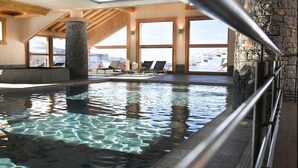 An indoor swimming pool with clear water, stone pillars, and wooden beams. - CGH Résidences & Spas Les Granges du Soleil (La Plagne-Tarentaise)