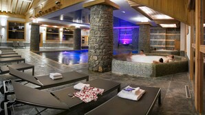 Un área de spa con pilares de piedra, una piscina y sillones de descanso.