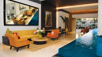Un vestíbulo de hotel con piscina, zonas de estar y una gran fotografía enmarcada en la pared.