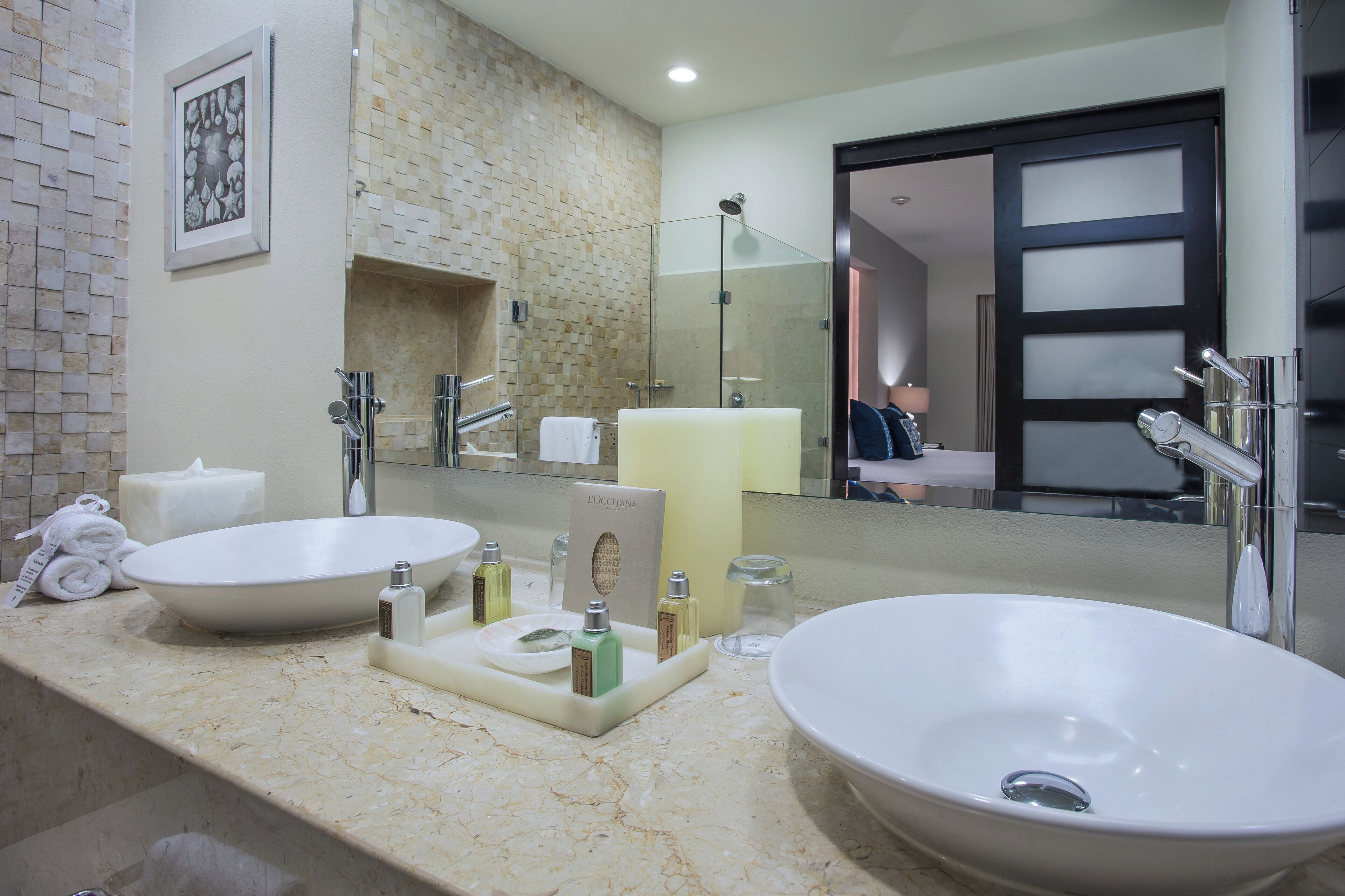 A bathroom with two sinks, a large mirror, and a shower.