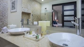 A bathroom with two sinks, a large mirror, and a shower.