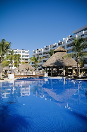 Relax by the pool surrounded by lounge chairs and umbrellas, with hotel rooms above.