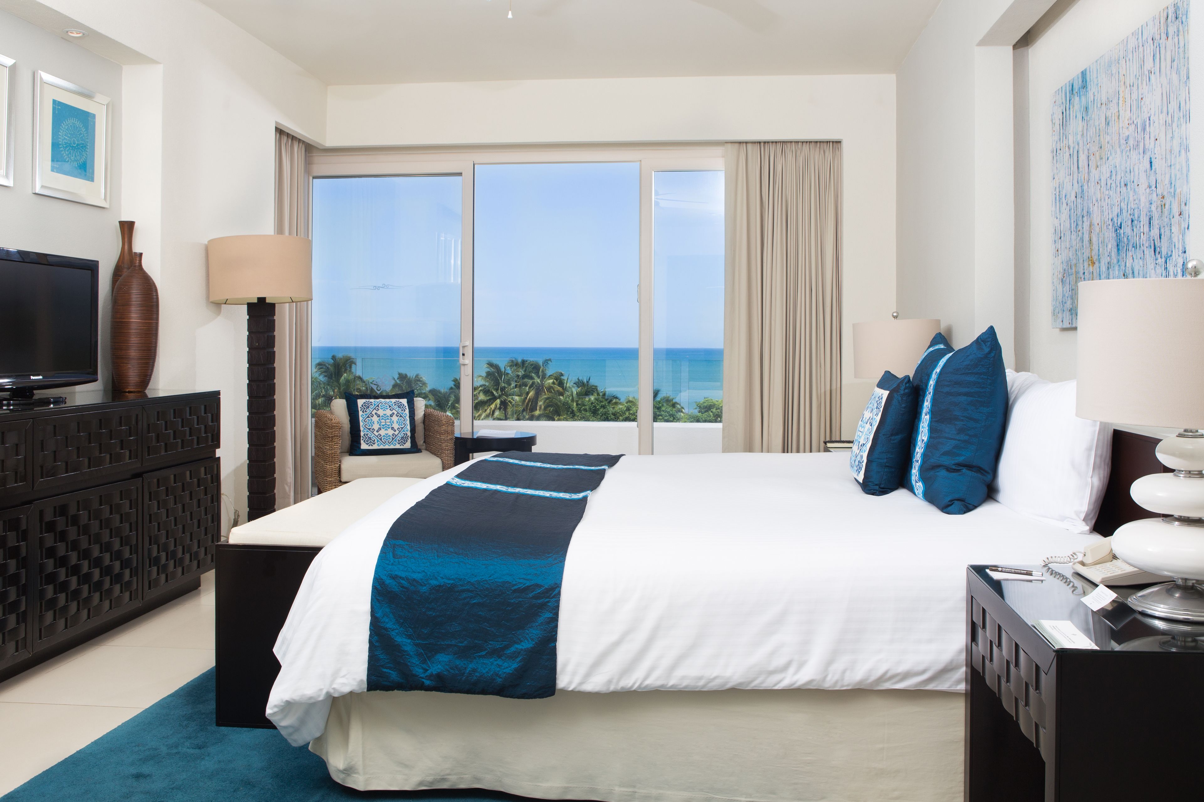 Habitación de hotel con una cama grande, televisión, escritorio y vista al océano.
