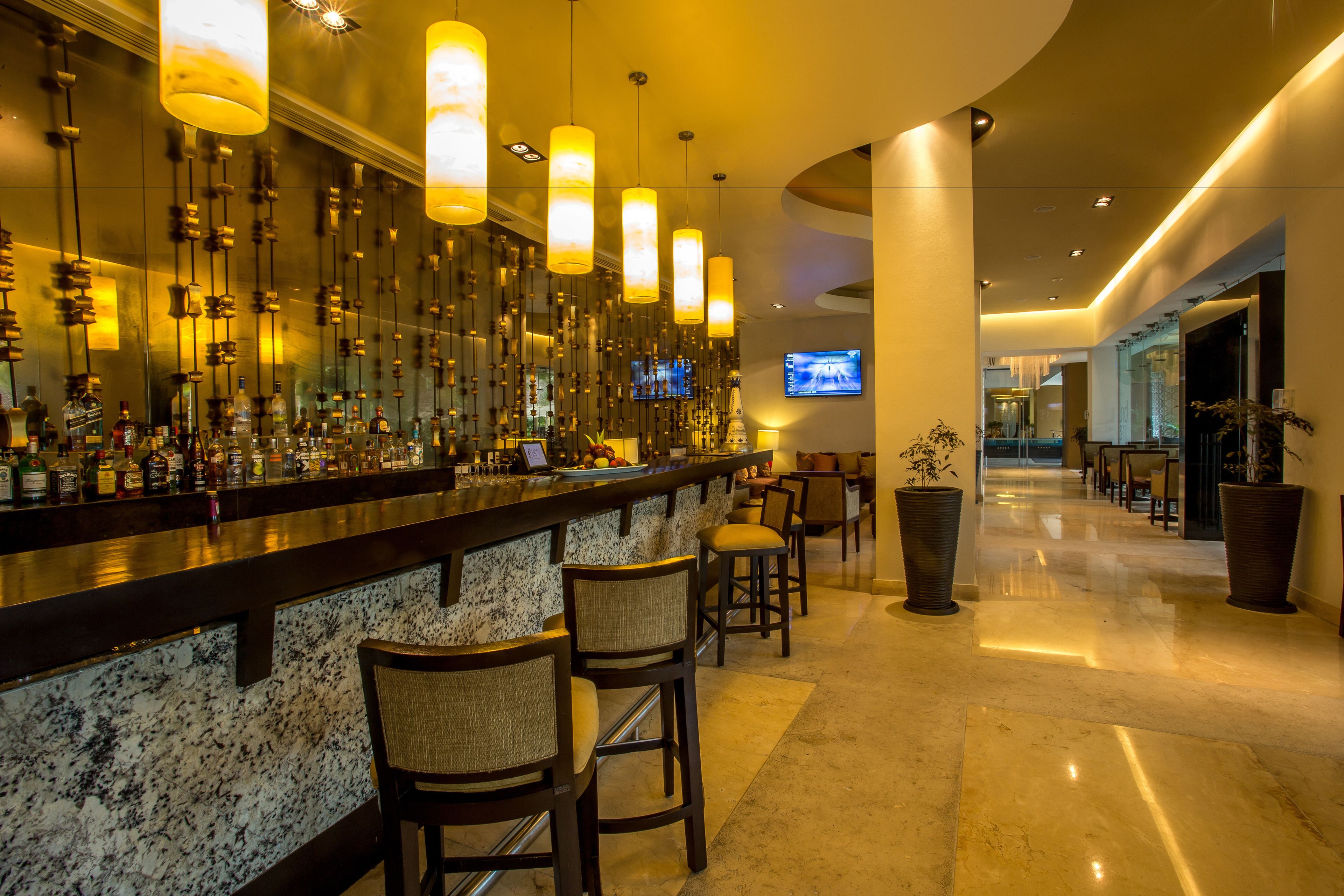 A bar area with a marble countertop, hanging pendant lights, and several bar stools.