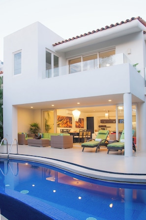 Relax by the pool in this home's inviting outdoor space, featuring a dining area and lounge chairs.