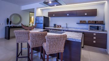 Una cocina moderna con una isla central, taburetes de bar, un microondas y un refrigerador.