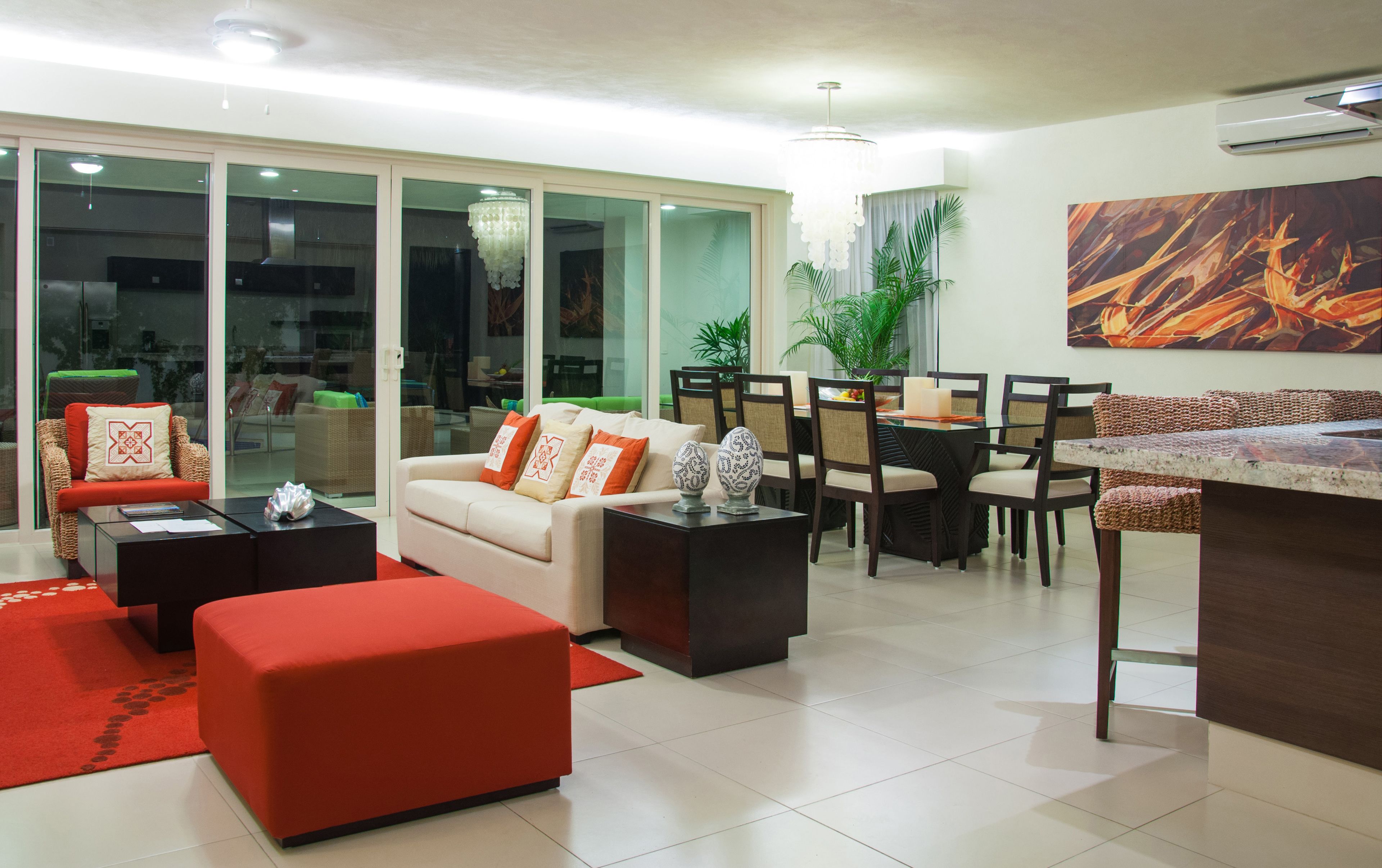 Un salon moderne comprenant un canapé, un pouf et un coin repas avec des chaises et une table.