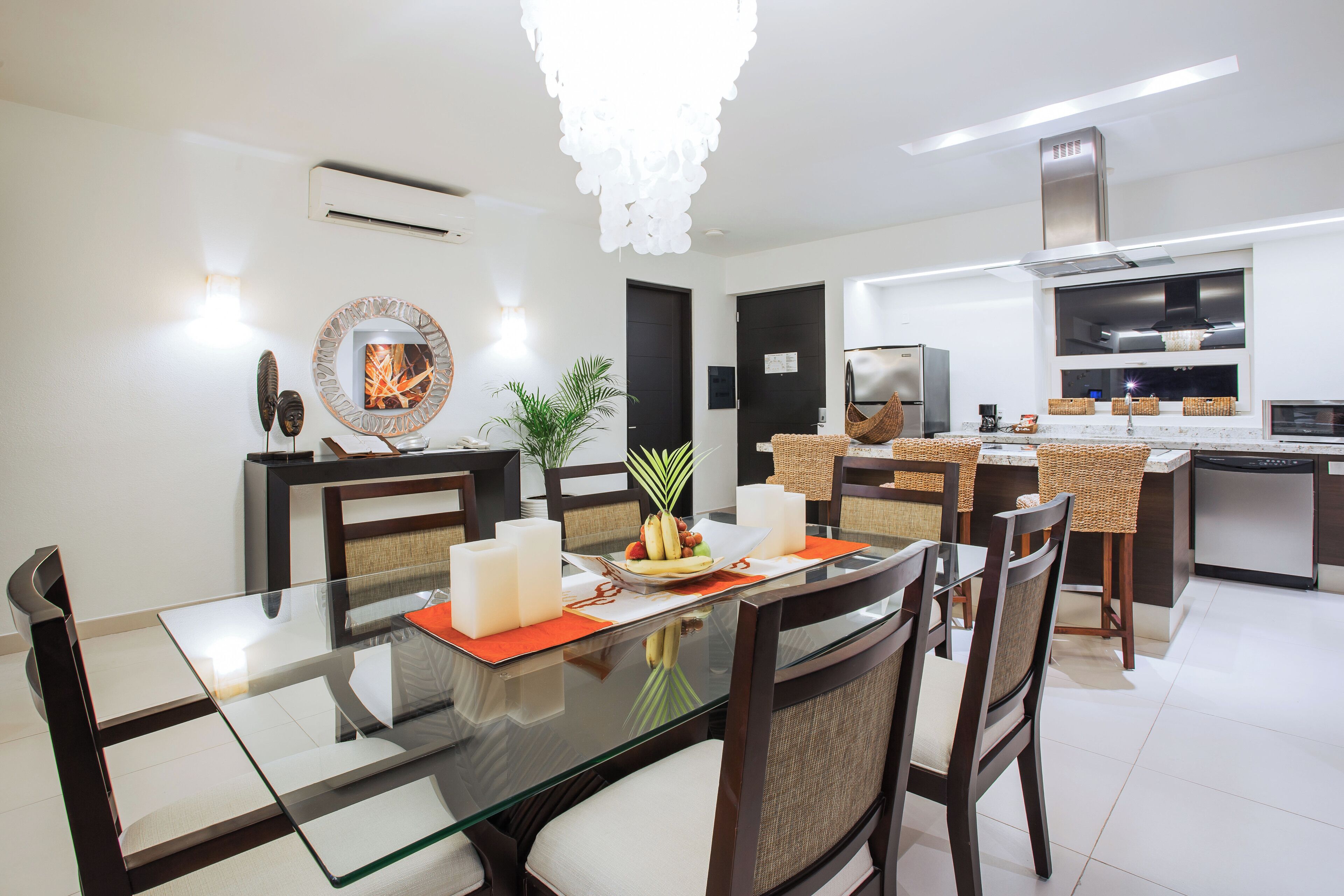 A modern kitchen with a central island, built-in appliances, and a dining area with a glass table and chairs.