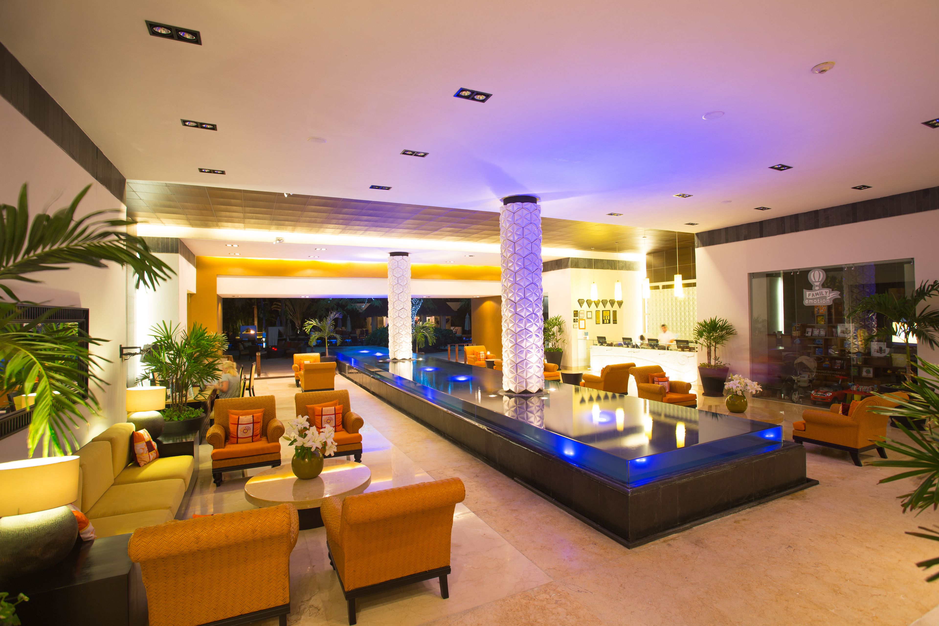 A modern lobby with a central pool, comfortable seating, and a reception area.