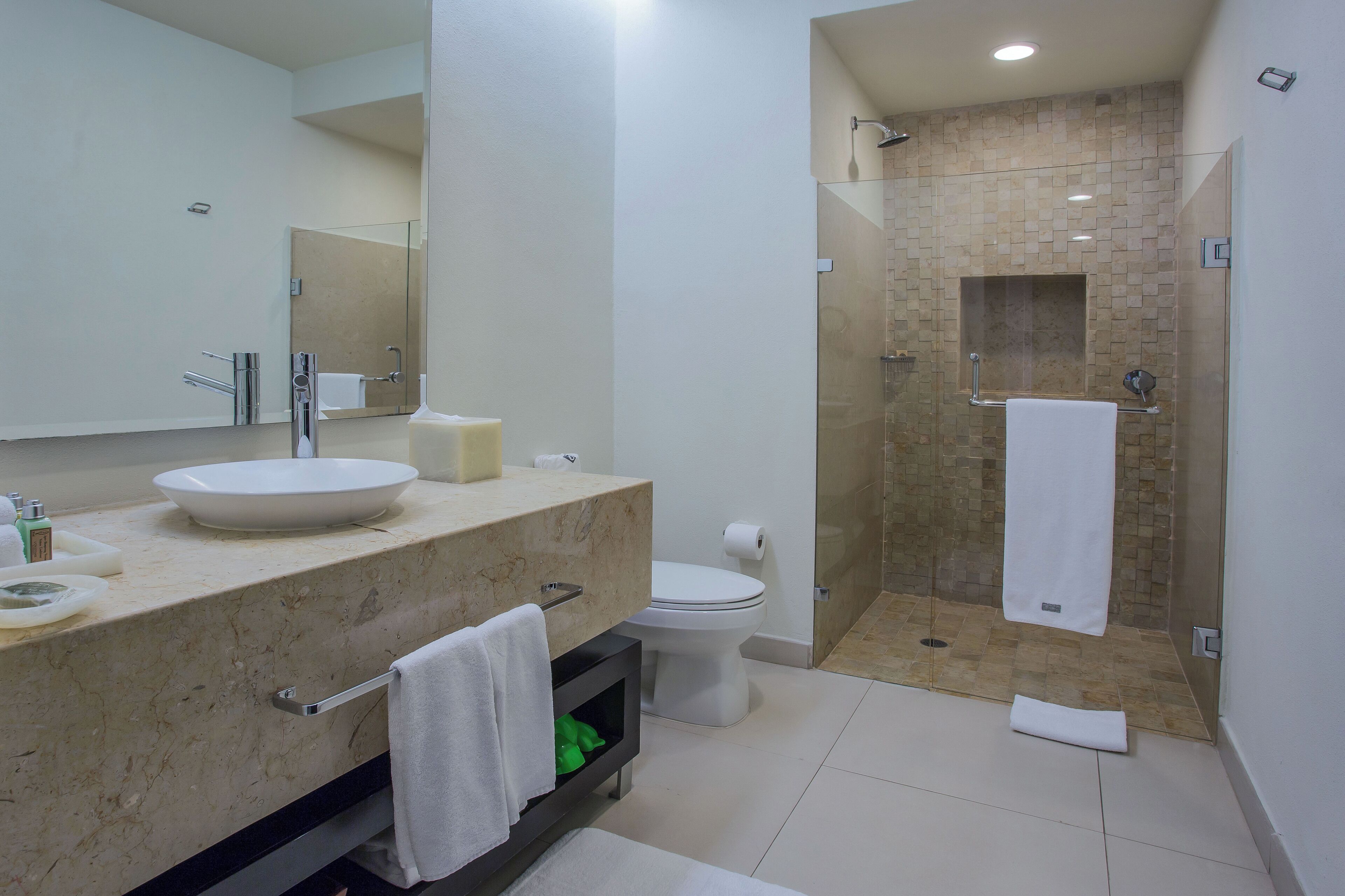 Un baño moderno con un lavamanos grande, inodoro y ducha a ras de suelo.