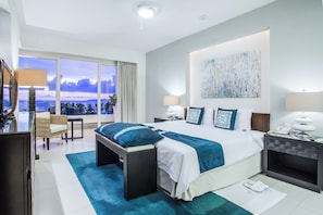 Relax in a spacious room with a large bed, seating area, and desk, offering a view of the sky.