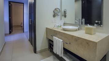 Un baño moderno con un lavamanos grande, espejo y armarios oscuros.
