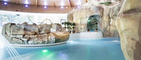 An indoor swimming pool with rock formations and a wooden ceiling.