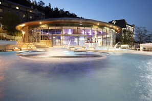 A modern building with a glass facade, a pool, and a staircase leading to the entrance. - Hotel Princesse Flore (Royat)